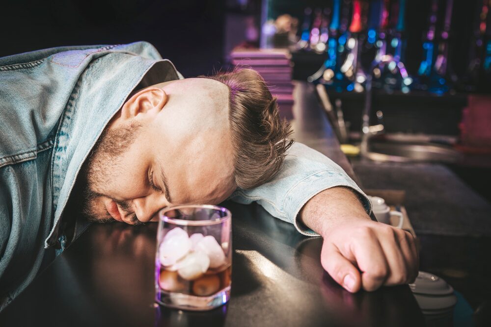 man having difficulty remaining conscious because of alcohol