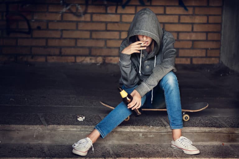 Teen girl holding a beer and smoking on steps 768x512 1