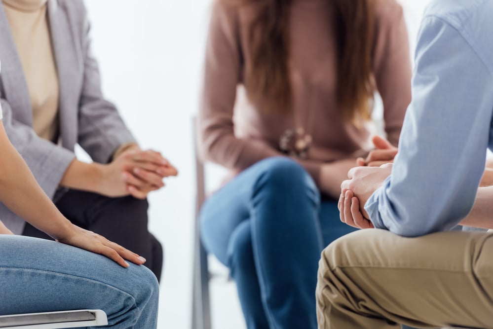 people sitting in therapy session with hands together