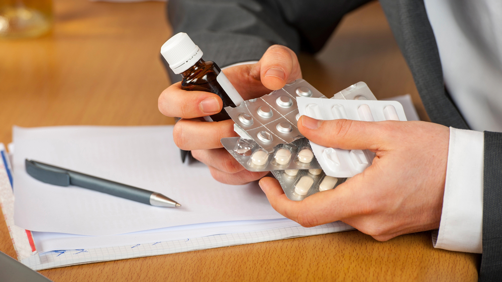 man holding widely prescribed painkillers