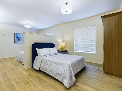 a serene double bedroom with 2 windows and a large dresser