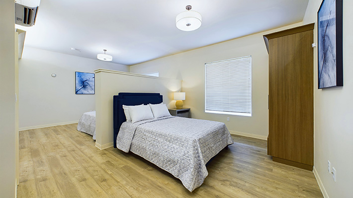 a serene double bedroom with 2 windows and a large dresser