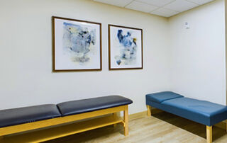 a massage room with 2 massage benches and 2 paintings