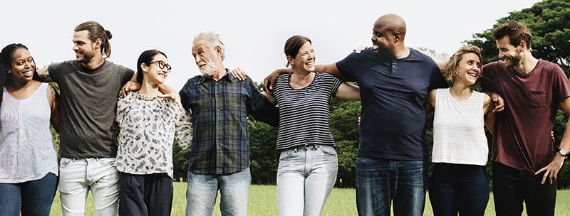 eight people of mixed backgrounds, arm to arm, and smiling at eachother.